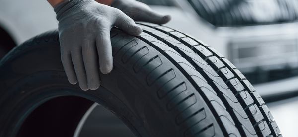 Une main gantée qui pousse un pneu