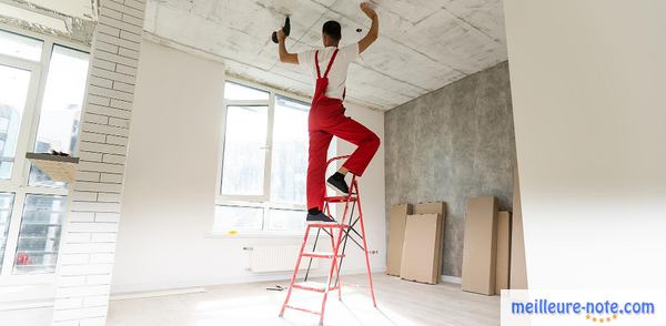 homme en salopette rouge visant des plaques au plafond