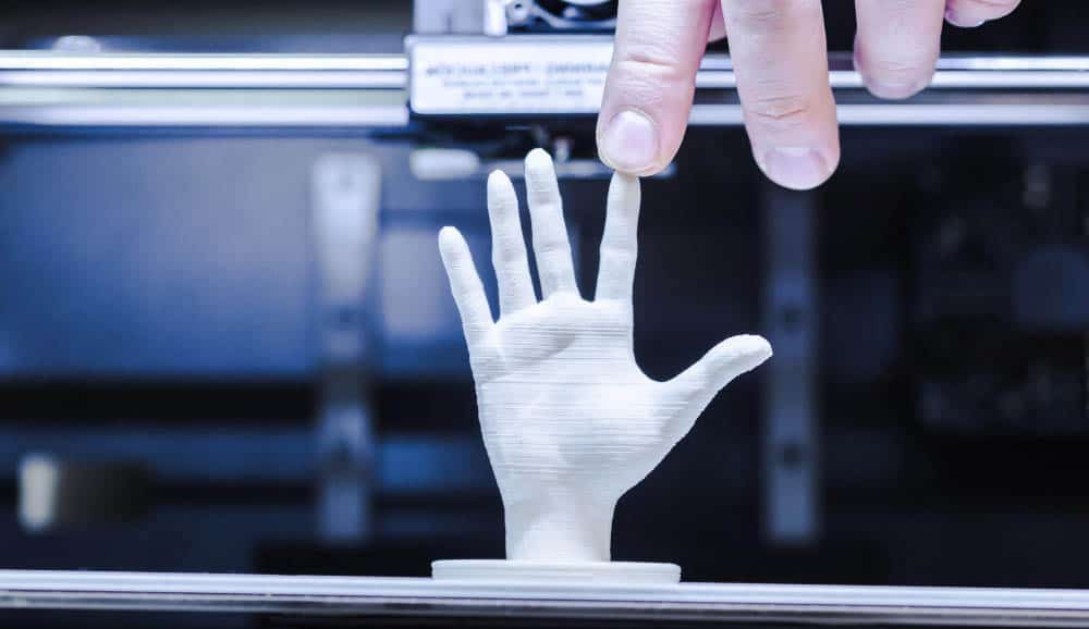 main humaine qui touche le doigt d'une main fabriquée avec une imprimante 3D