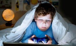 enfant dans son lit jouant aux jeux vidéo