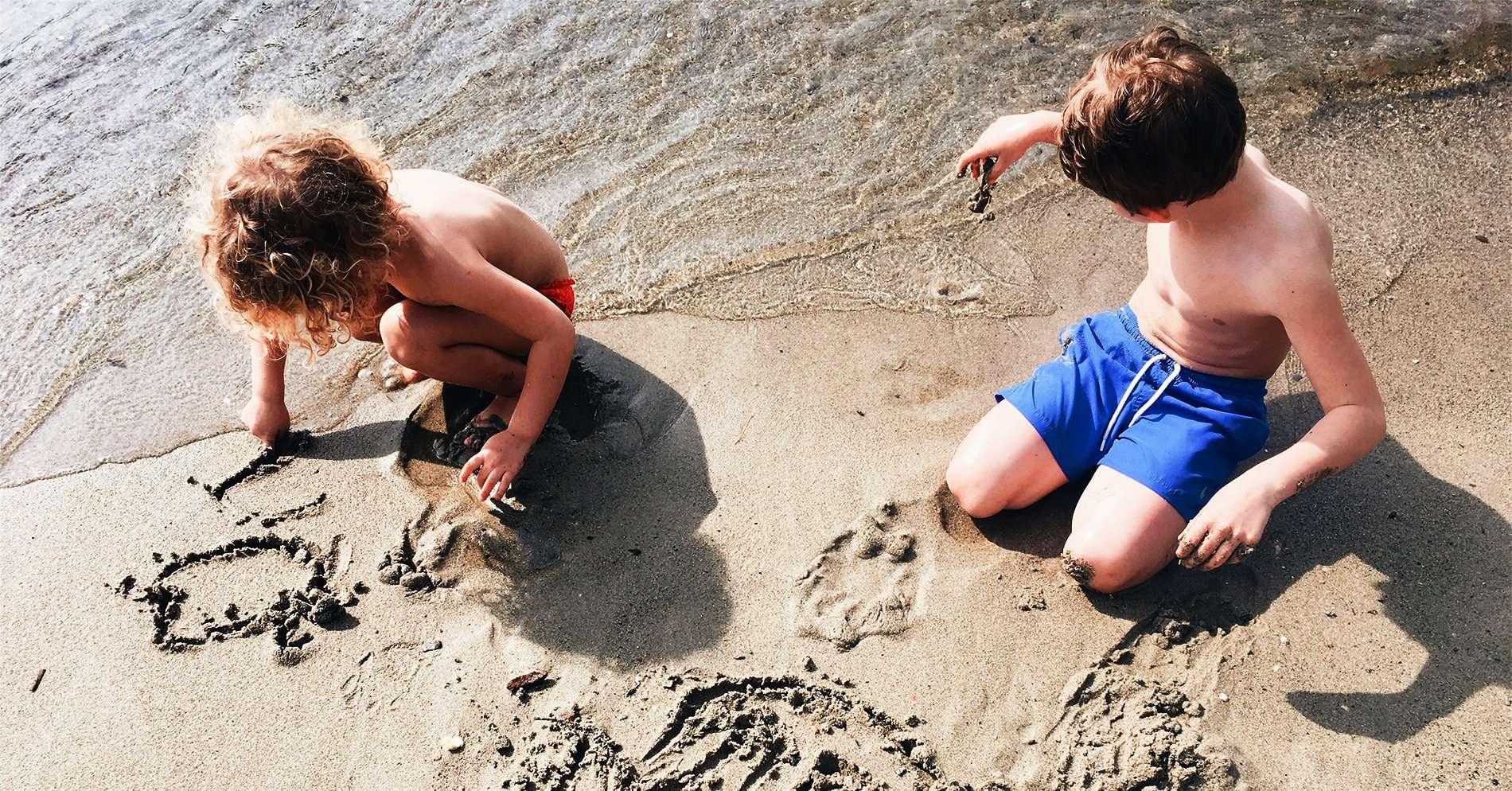 enfants faisant des dessins sur le sable