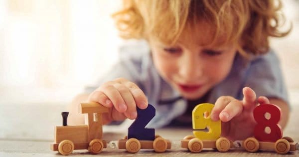 enfant jouant avec un train en bois