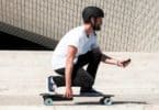 homme muni de casque avec son skateboard electrique