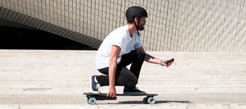 homme muni de casque avec son skateboard electrique