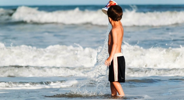 petit garçon jouant l'eau de mer avec un seau