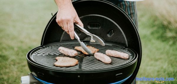 Une main qui prend un saucisse sur le grill électrique