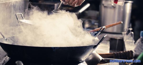 une main prépare sa nourriture avec un wok électrique