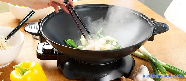 une main qui mélange le met dans un wok avec des baguettes 