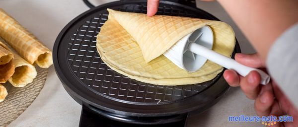 Un crêpière électrique et une main qui tourne la crêpe