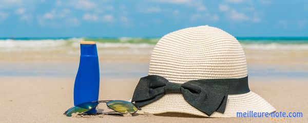Une paire de lunette et un chapeau accompagné d'une crème solaire