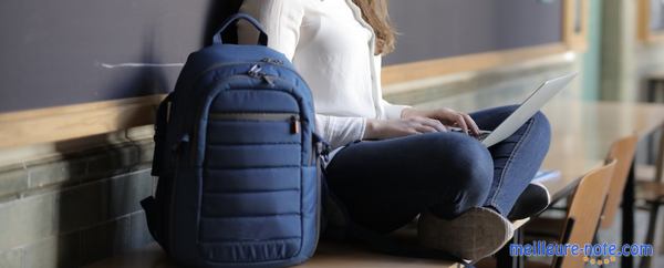 Une étudiante assise avec un sac à dos pour ordinateur portable bleu