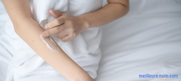 une femme met de la crème sur sa peau