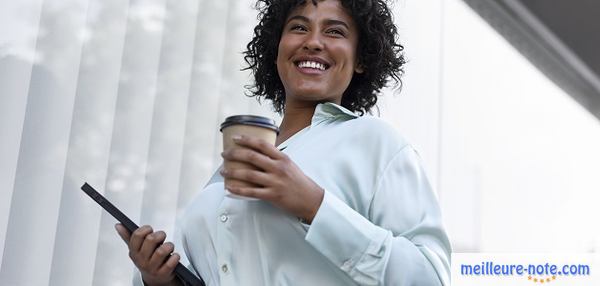 Une femme qui boit son café et tient une tablette