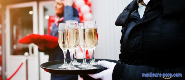 un serveur porte des verre de crémant