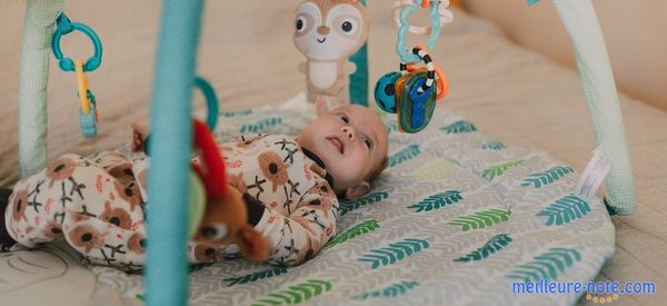 Un petit bébé allonger sur un tapis d'éveil