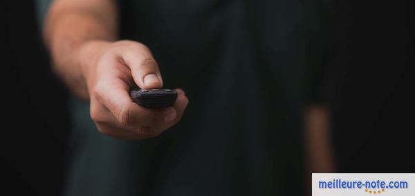 un homme clique une télécommande noire