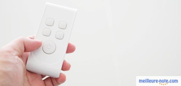 une main qui porte une télécommande blanche 