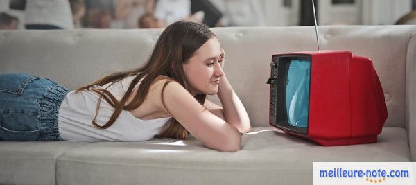 une jeune fille qui regarde la télé sur son canapé