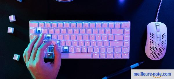 Une main posée sur un clavier blanc et un souris gamer blanc