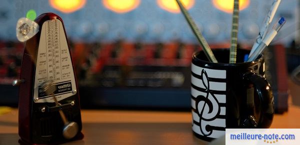Un métronome avec un mug plein de stylo