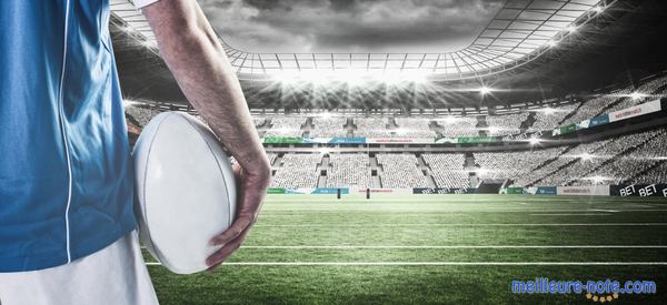 Un homme qui tient un ballon de rugby dans une stade