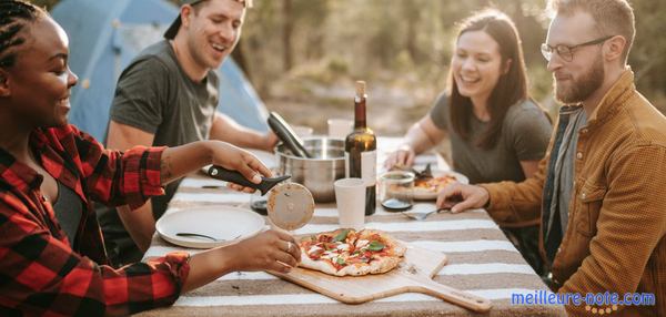 amis autour d'une table de picnic pour manger une pizza