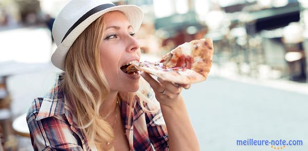 jeune femme avec chapeau mangeant une part de pizza