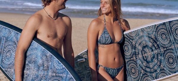 Un couple avec des planches de surf de marque Olaian - Decathlon