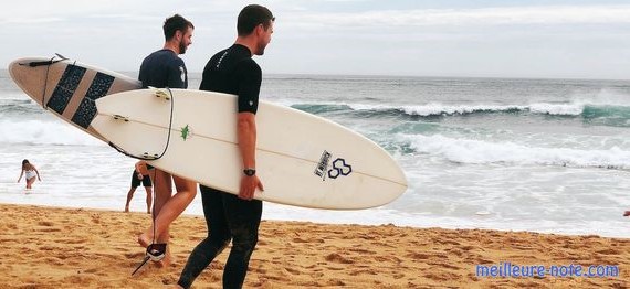 Deux hommes qui portent des planches de surf