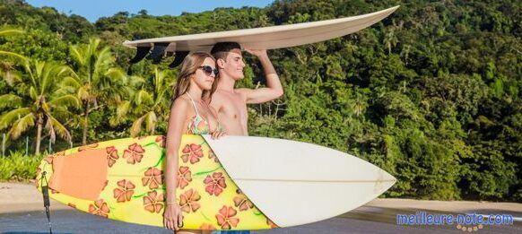 Deux jeunes qui portent des planches de surf