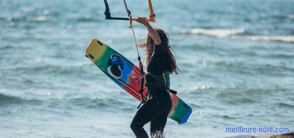 une femme tient une planche de kitesurf