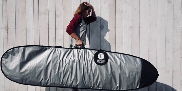 Une femme qui port une planche de surf dans une housse