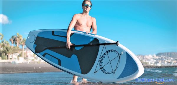 un homme porte son paddle gonflable bleu