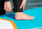 jeune fille qui attache son leash de paddle