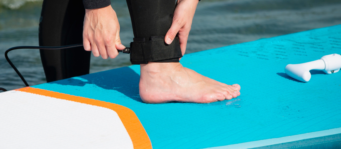 jeune fille qui attache son leash de paddle