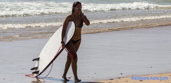 Une fille qui sort de la mer avec un leash et un planche de surf