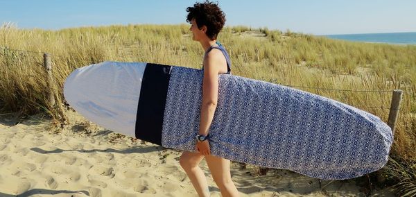 Une femme qui port une housse de planche de surf