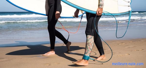 Deux personnes qui portent des planches de surf et des leash