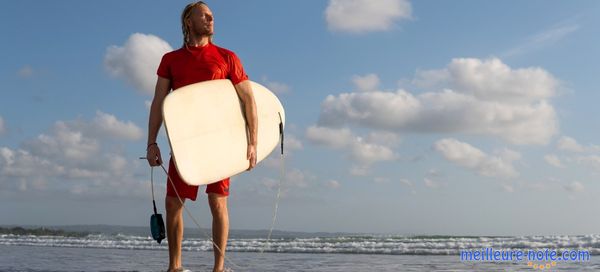 Un surfeur qui tient son planche de surf