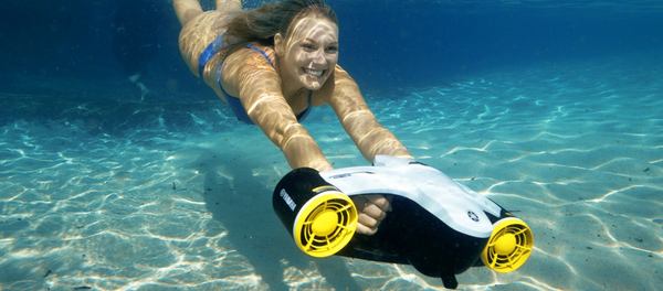 une femme sourit portant son scooter sous marin