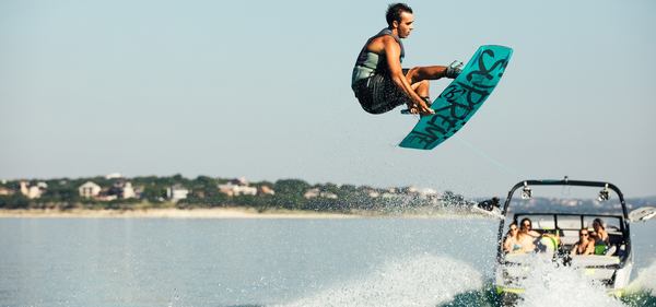 un homme avec son wakeboard est tiré par un bateau