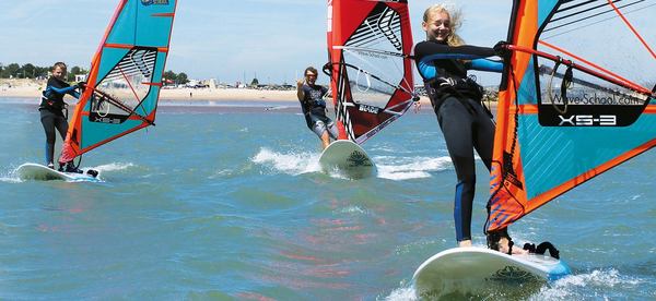 une femme porte son harnais avec un windsurf