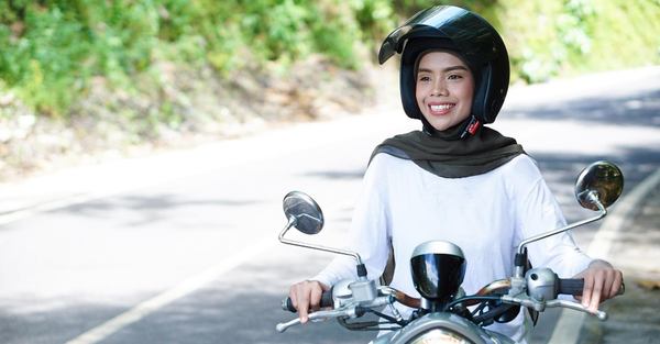 une femme sourit avec sa moto