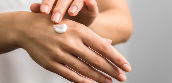 une femme masse sa peau avec la crème