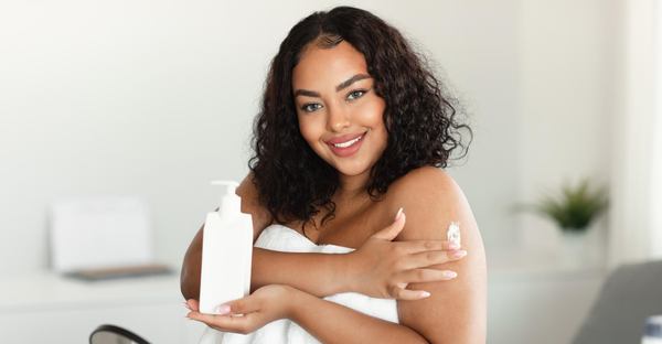 une femme sourit utilise une crème pour la peau 
