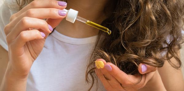 une femme utilise l'huile pour cheveux