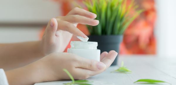 une main tenait une boîte de crème pour la peau