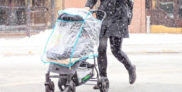 une femme pousse une poussette avec un habillage pluie